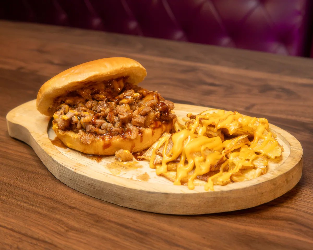 Bollo de brisket ahumado servido con papas en Cancún