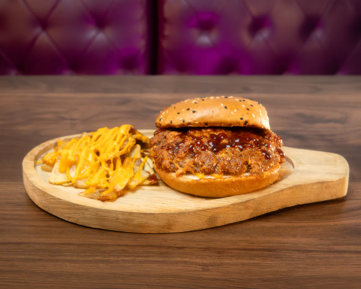Bollo de pulled pork ahumado servido con papas en Cancún
