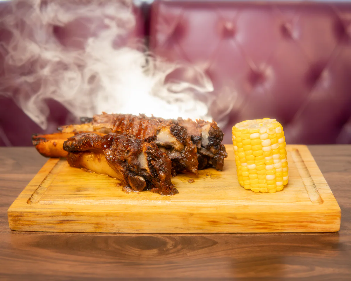 Medio costillar de res BBQ ahumado con tiras de elote en Cancún